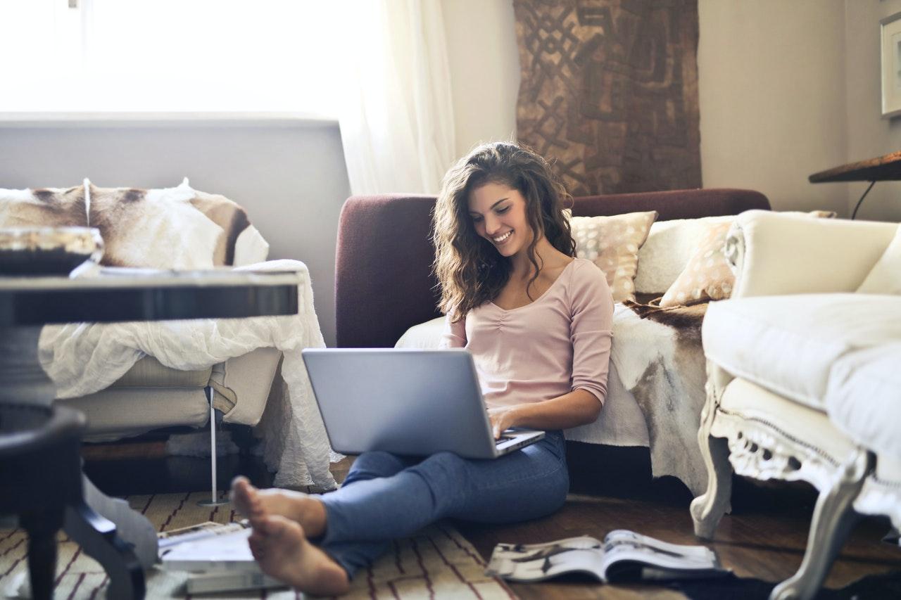 Single brunette woman smiling while using laptop